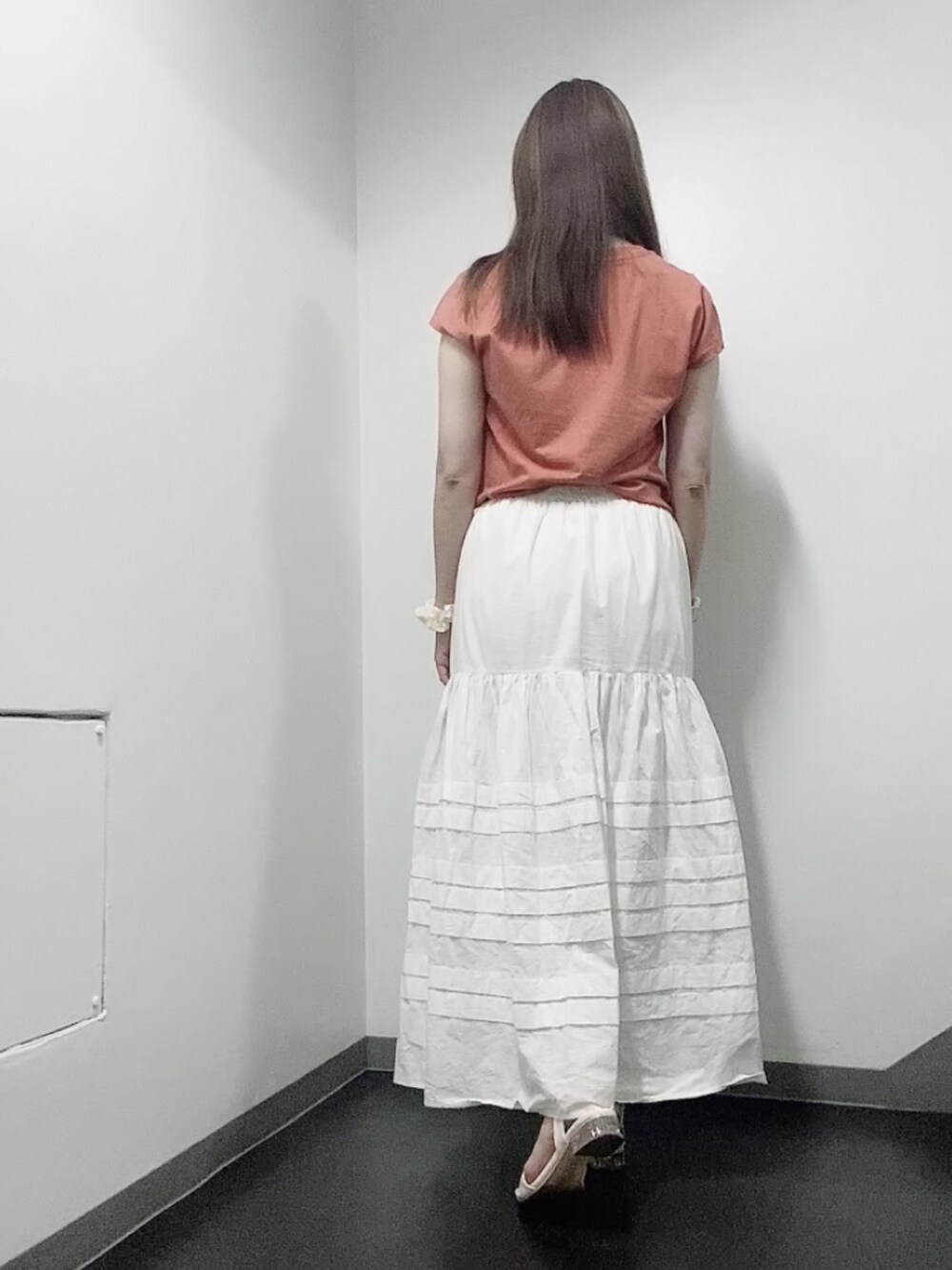 オレンジ系のTシャツ/カットソー、ホワイト系のスカート、ホワイト系のサンダルを着用したレディースの夏コーディネートの3枚目の写真