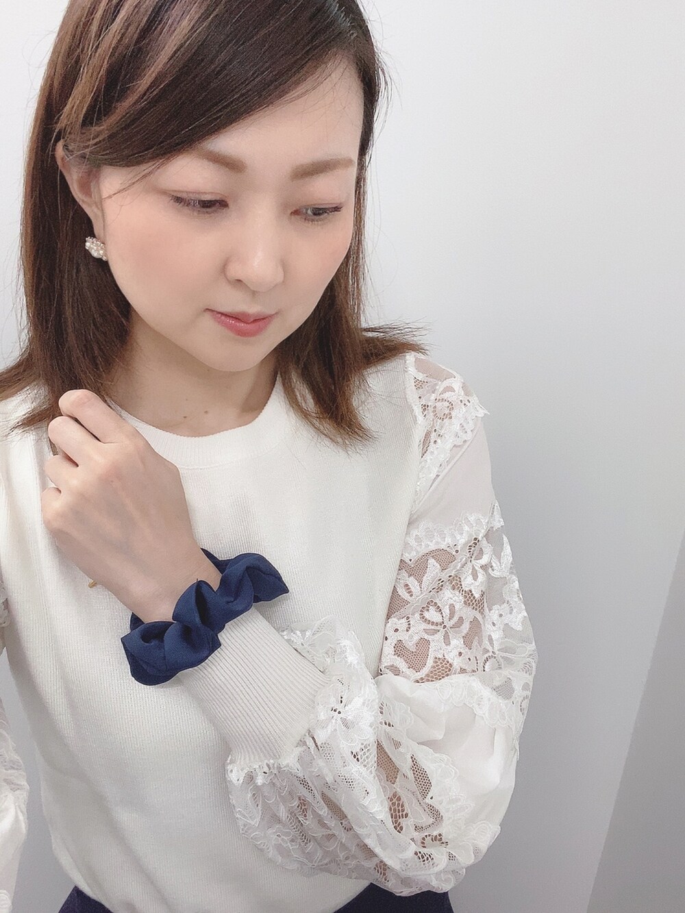 ホワイト系のニット/セーター、ブルー系のスカート、ブラック系のパンプスを着用したレディースの春コーディネートの4枚目の写真