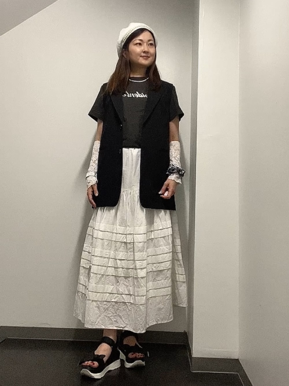 グレー系のTシャツ/カットソー、ホワイト系のスカート、ブラック系のベストを着用したレディースの夏コーディネートの3枚目の写真