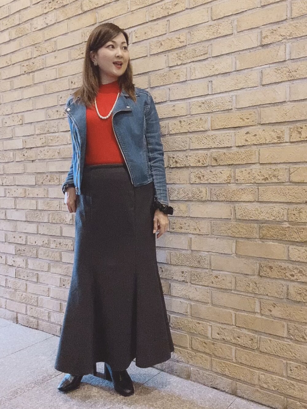 レッド系のニット/セーター、ブラック系のスカート、ブラック系のブーツを着用したレディースの秋コーディネートの2枚目の写真