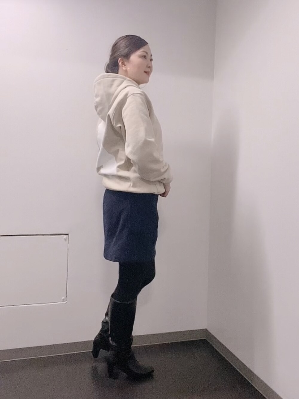 ベージュ系のパーカー、ブルー系のスカート、ブラック系のブーツを着用したレディースの冬コーディネートの2枚目の写真