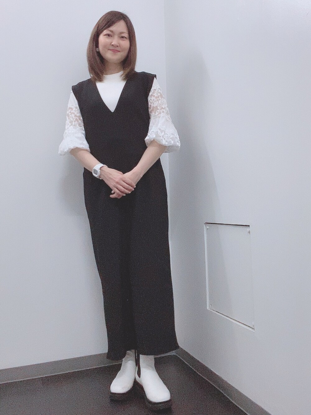 ホワイト系のニット/セーター、ブラック系のジャンパースカート、ホワイト系のレインシューズを着用したレディースの春コーディネートの2枚目の写真