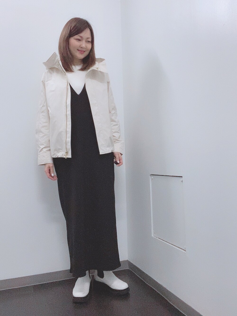 ホワイト系のニット/セーター、ブラック系のジャンパースカート、ホワイト系のレインシューズを着用したレディースの春コーディネートの4枚目の写真