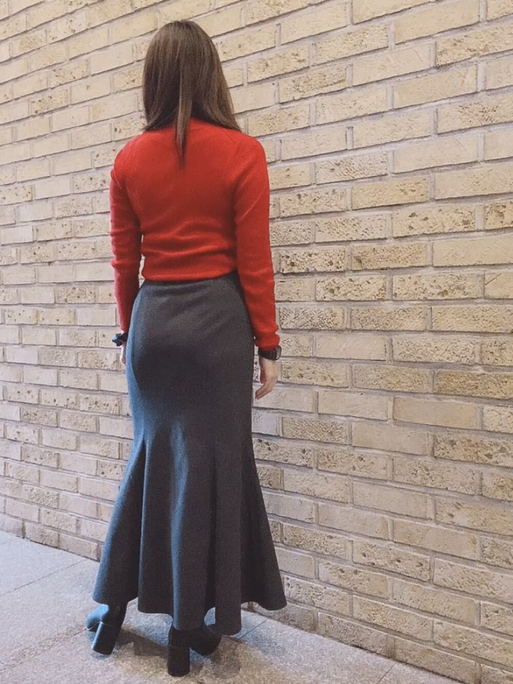 レッド系のニット/セーター、ブラック系のスカート、ブラック系のブーツを着用したレディースの秋コーディネートの4枚目の写真