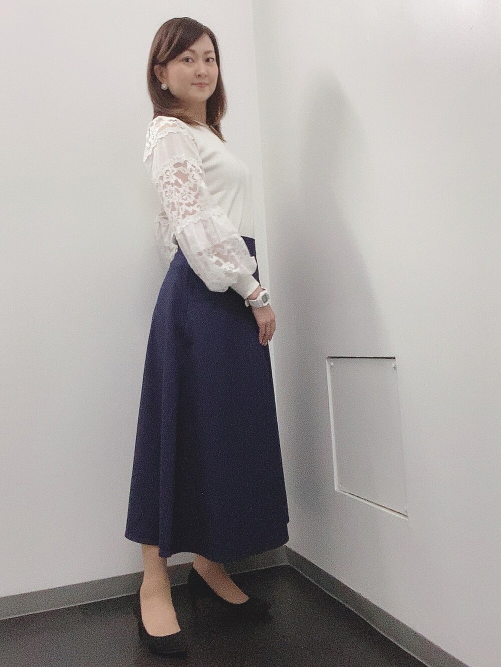 ホワイト系のニット/セーター、ブルー系のスカート、ブラック系のパンプスを着用したレディースの春コーディネートの2枚目の写真