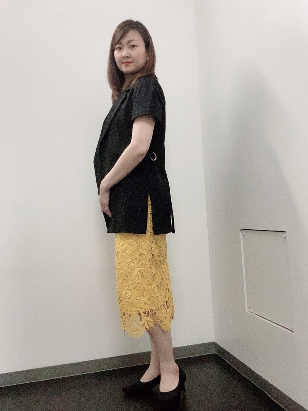 ブラック系のTシャツ/カットソー、イエロー系のスカート、ブラック系のパンプスを着用したレディースの夏コーディネートの2枚目の写真