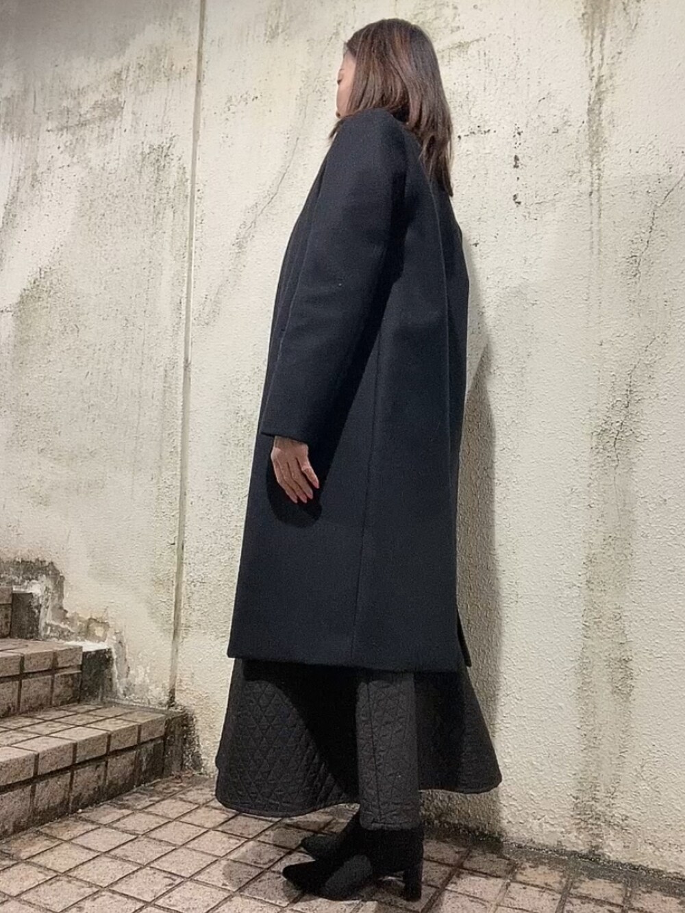 ブラック系のスカート、グリーン系のニット/セーター、ブラック系のブーツを着用したレディースの冬コーディネートの2枚目の写真