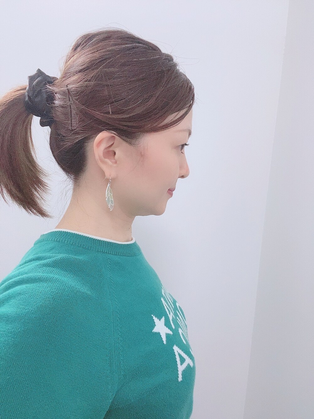 グリーン系のニット/セーター、ブラック系のスカート、ブラック系のレインシューズを着用したレディースの春コーディネートの4枚目の写真