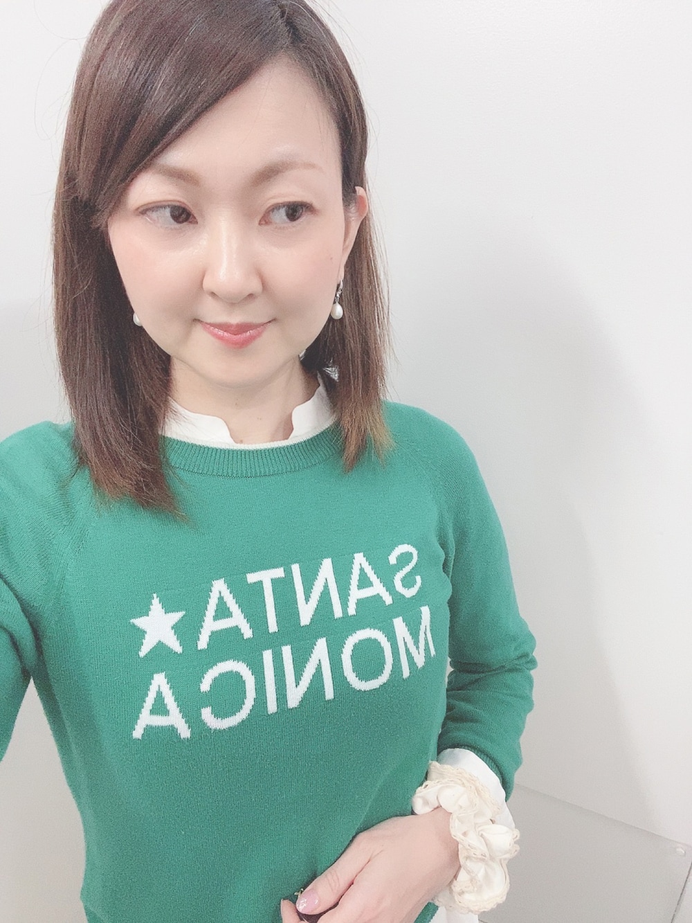 グリーン系のニット/セーター、ホワイト系のスカート、ホワイト系のサンダルを着用したレディースの春コーディネートの3枚目の写真