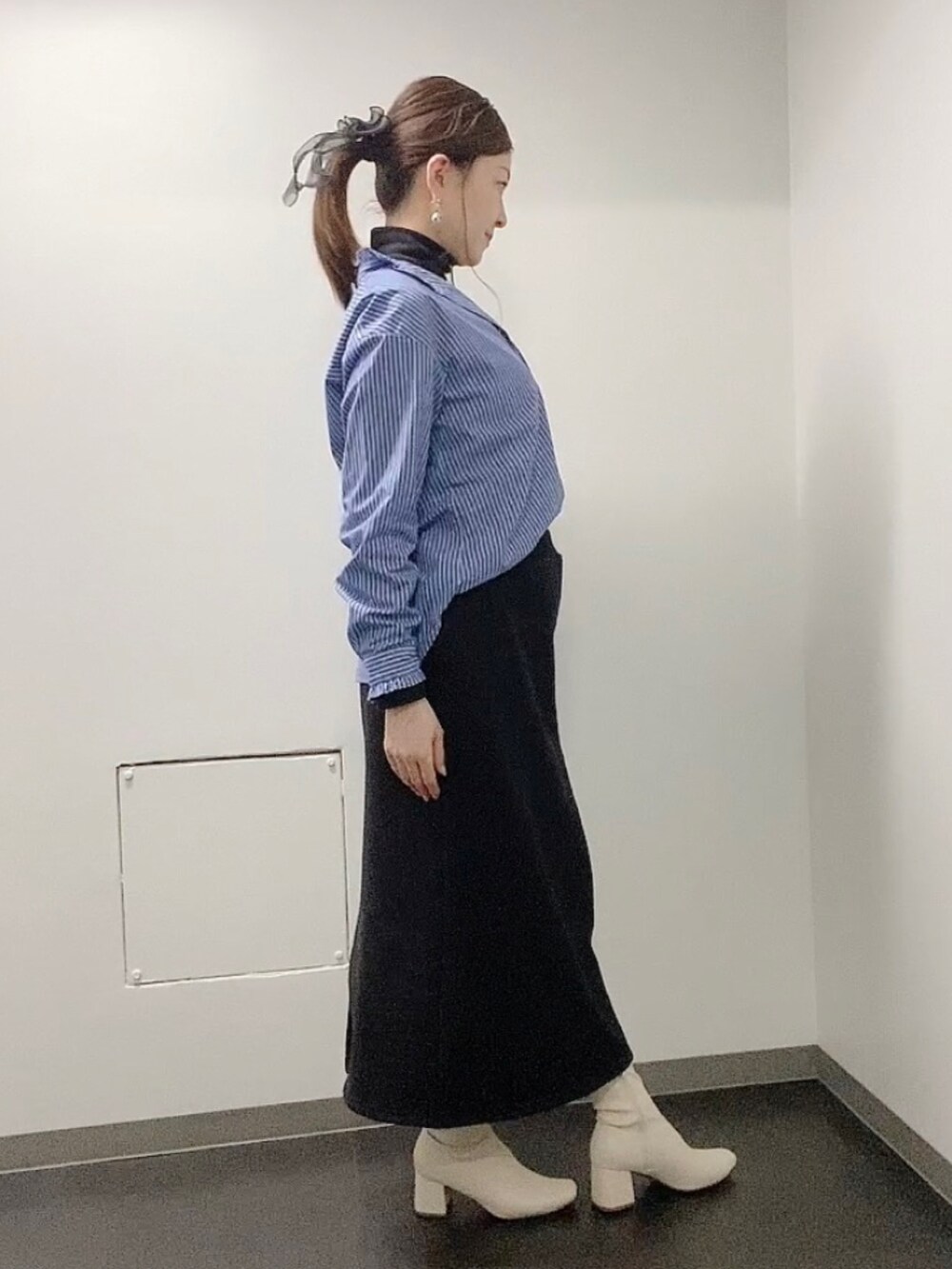 ブラック系のスカート、ホワイト系のブーツ、ブルー系のシャツ/ブラウスを着用したレディースの冬コーディネートの2枚目の写真