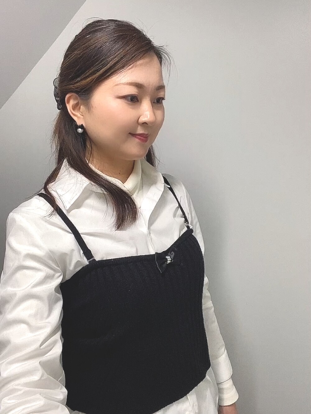 ブラック系のニット/セーター、ホワイト系のシャツ/ブラウス、ブルー系のデニムパンツを着用したレディースの春コーディネートの5枚目の写真