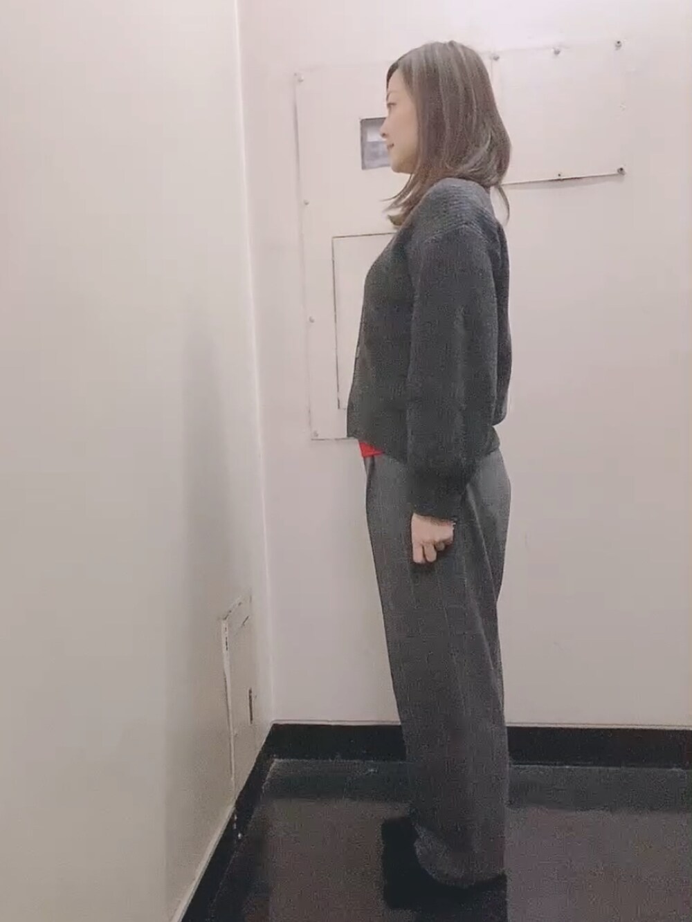レッド系のニット/セーター、グレー系のスラックス、ブラック系のモカシン/デッキシューズを着用したレディースの冬コーディネートの3枚目の写真
