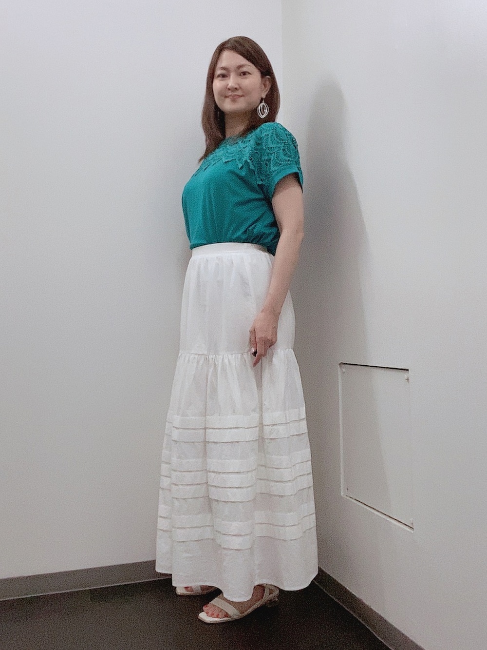ホワイト系のスカート、ホワイト系のサンダル、グリーン系のTシャツ/カットソーを着用したレディースの夏コーディネートの2枚目の写真