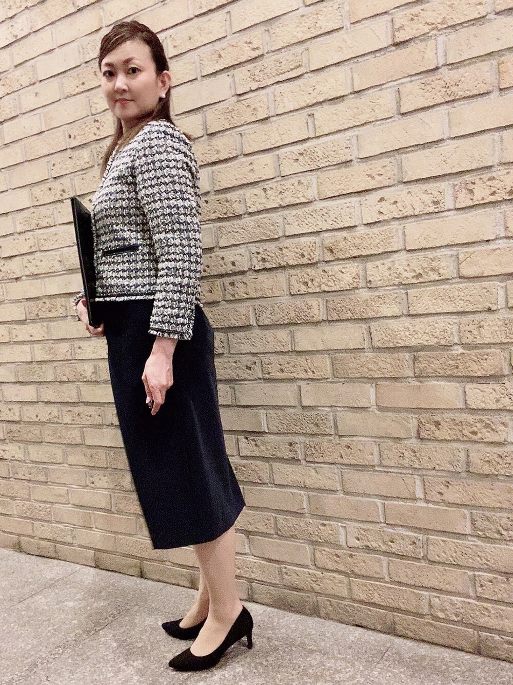 ブルー系のスーツセット、ブラック系のパンプス、ホワイト系のネックレスを着用したレディースの夏コーディネートの2枚目の写真