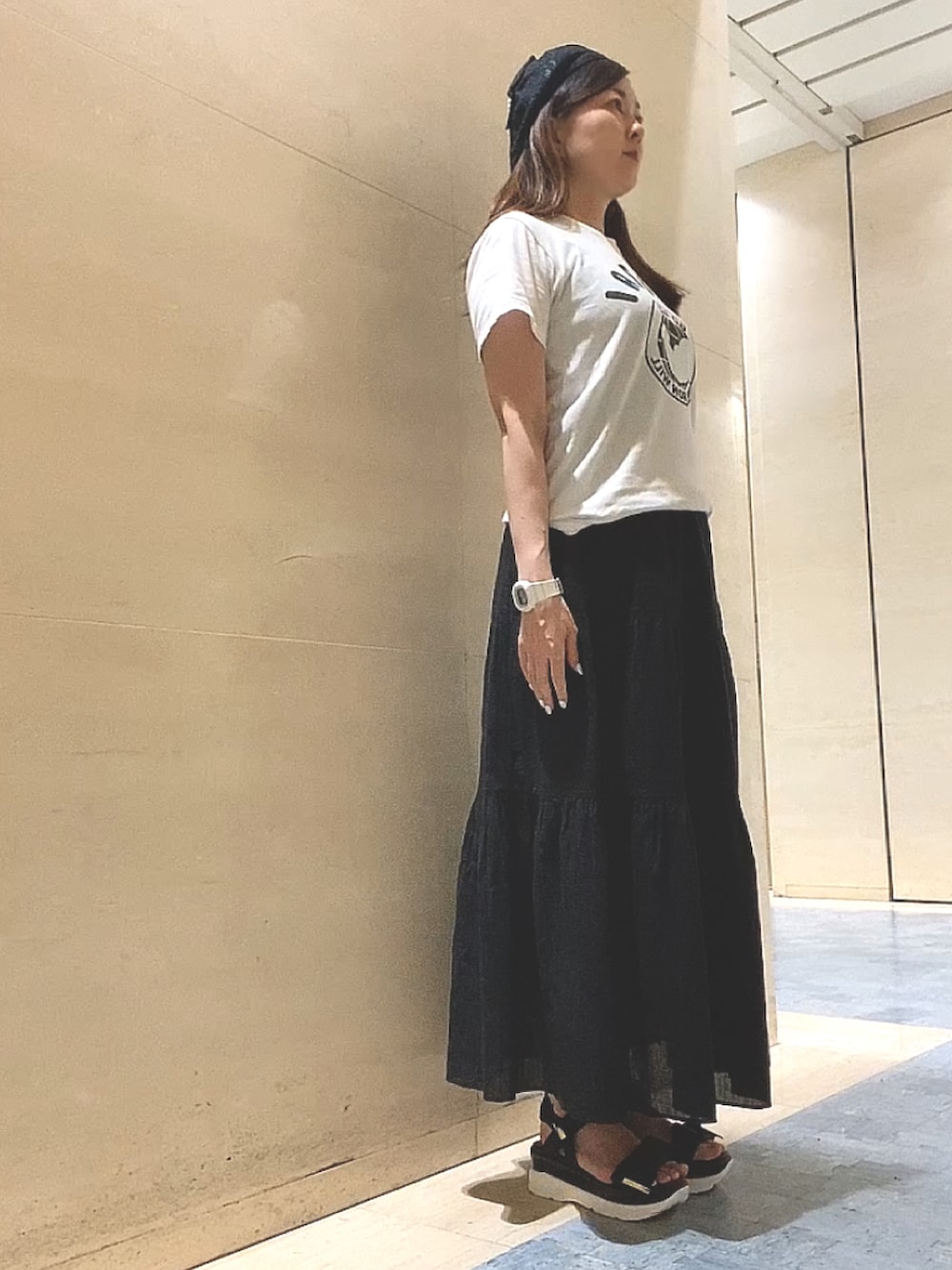 ブラック系のスカート、ブラック系のサンダル、ホワイト系のTシャツ/カットソーを着用したレディースの夏コーディネートの2枚目の写真