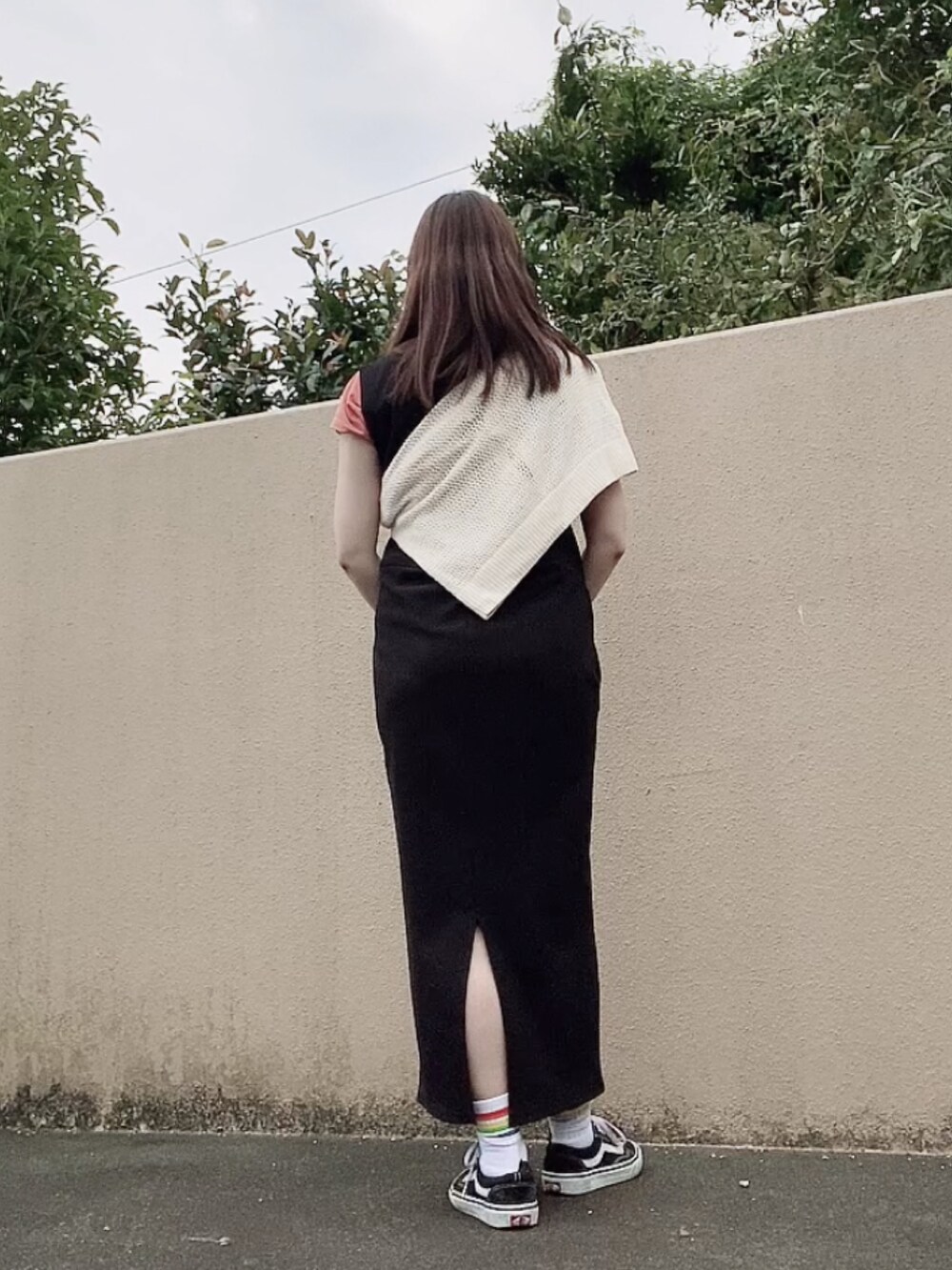 ブラック系のジャンパースカート、ホワイト系のカーディガン/ボレロ、オレンジ系のTシャツ/カットソーを着用したレディースの秋コーディネートの3枚目の写真