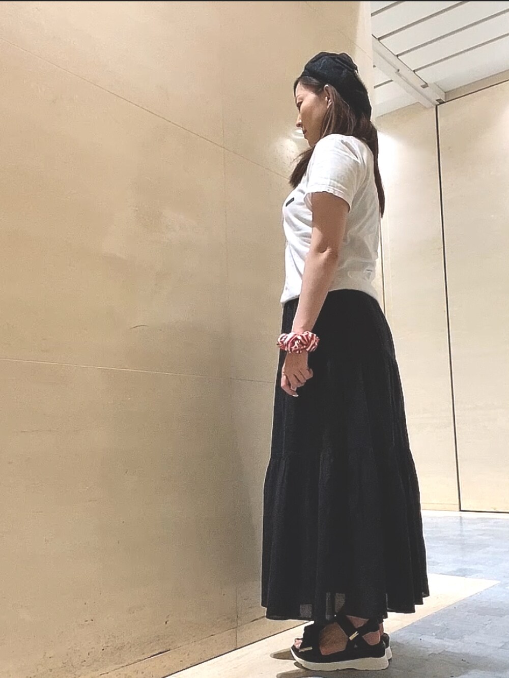 ブラック系のスカート、ブラック系のサンダル、ホワイト系のTシャツ/カットソーを着用したレディースの夏コーディネートの4枚目の写真