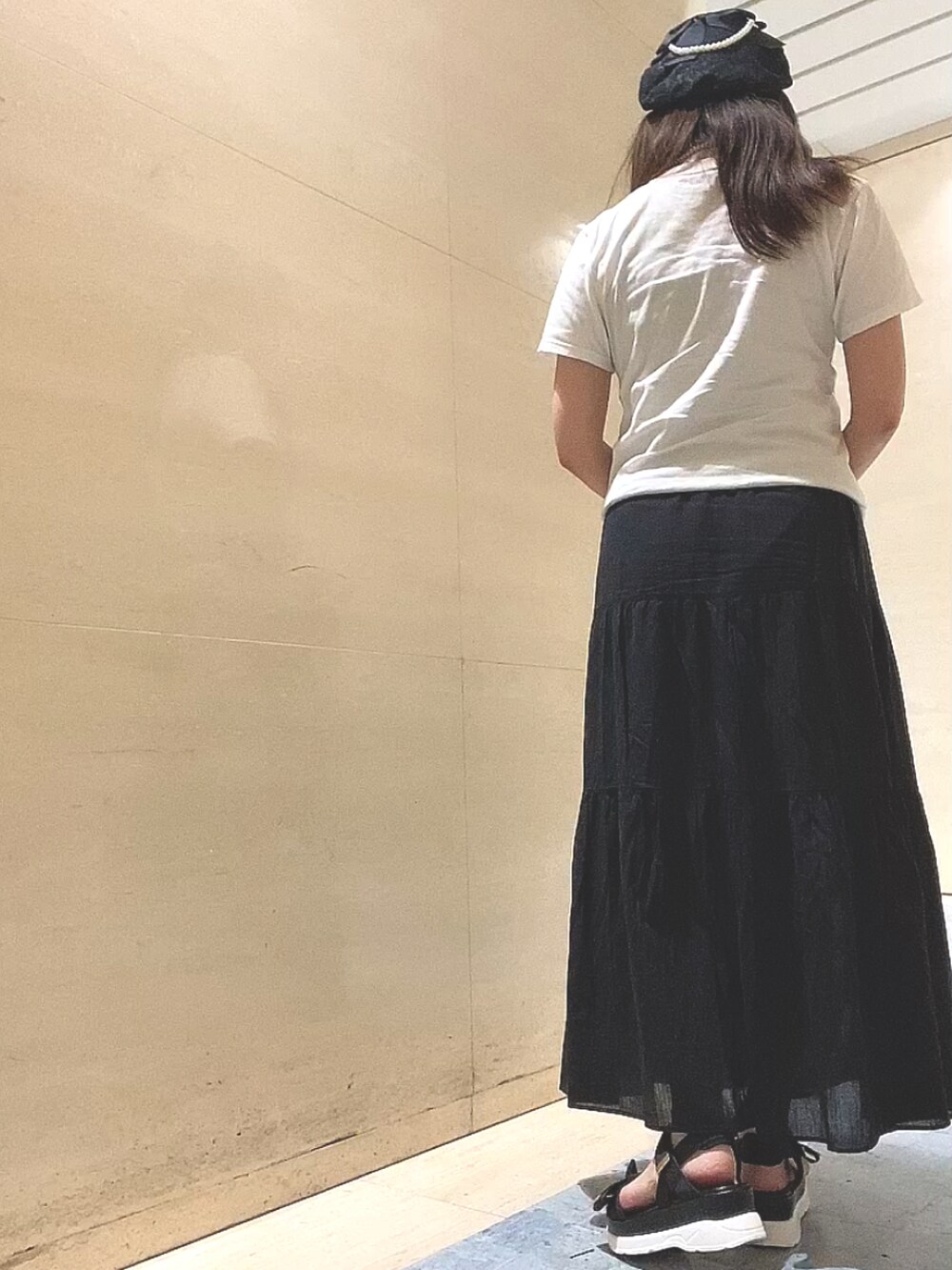 ブラック系のスカート、ブラック系のサンダル、ホワイト系のTシャツ/カットソーを着用したレディースの夏コーディネートの3枚目の写真