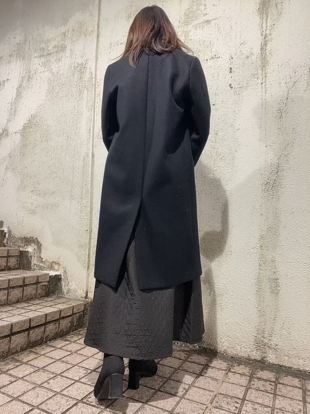 ブラック系のスカート、グリーン系のニット/セーター、ブラック系のブーツを着用したレディースの冬コーディネートの3枚目の写真