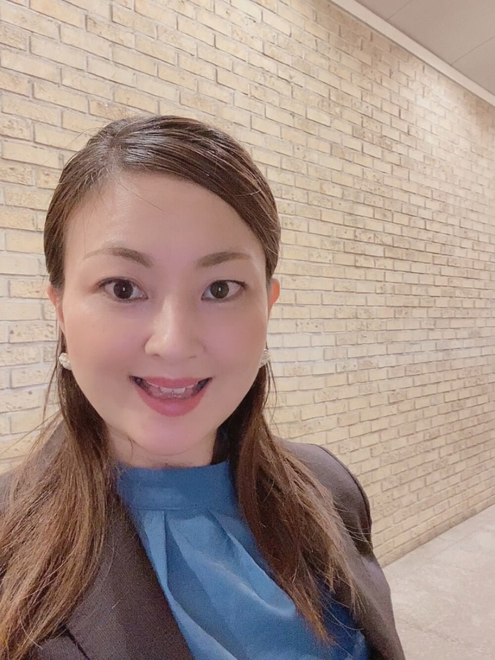 ブラウン系のスーツセット、グレー系のパンプス、ブルー系のシャツ/ブラウスを着用したレディースの秋コーディネートの4枚目の写真