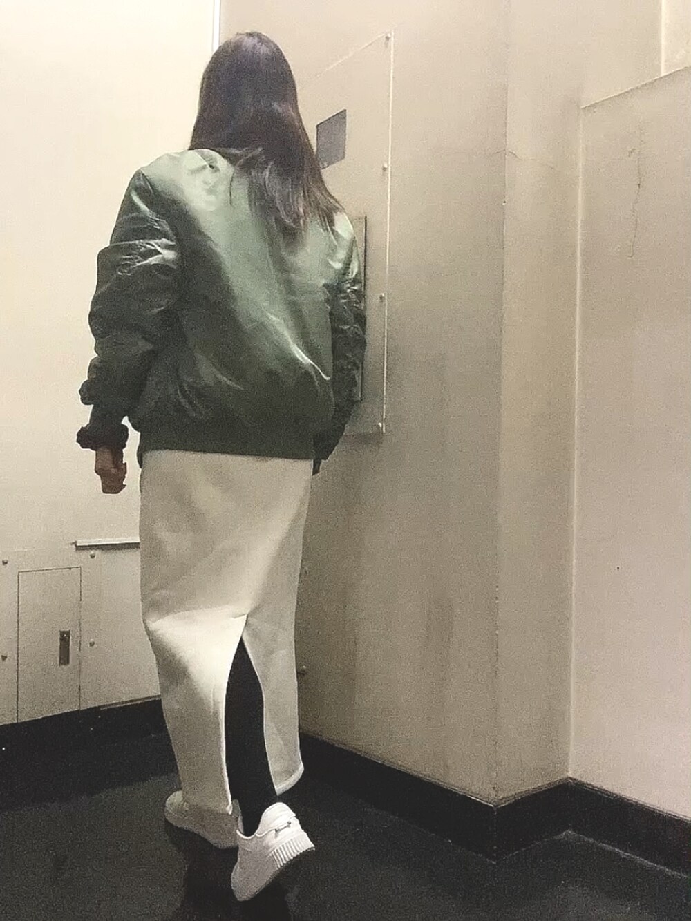 グリーン系のMA-1、ホワイト系のスカート、ホワイト系のスニーカーを着用したレディースの春コーディネートの3枚目の写真