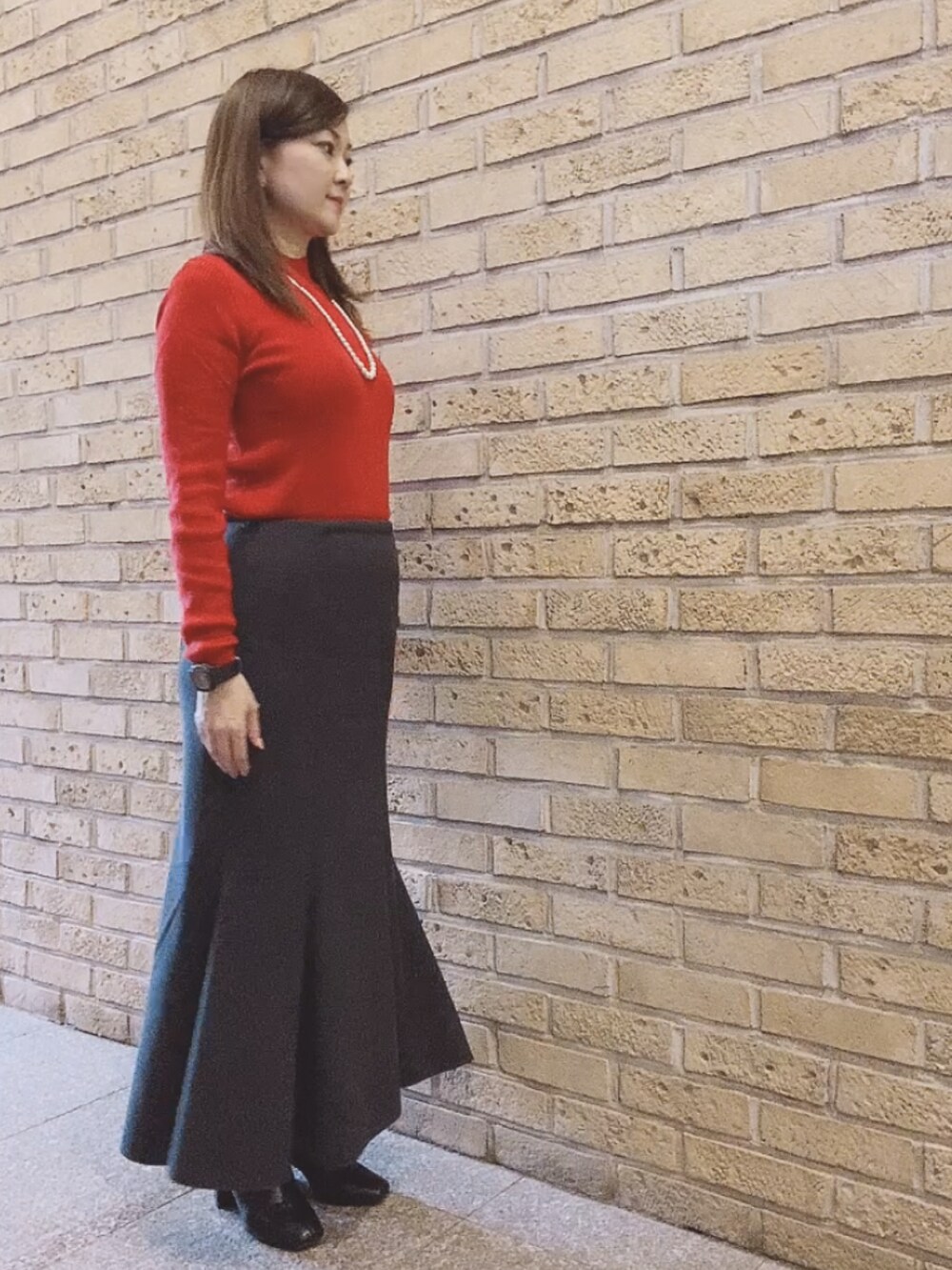 レッド系のニット/セーター、ブラック系のスカート、ブラック系のブーツを着用したレディースの秋コーディネートの3枚目の写真
