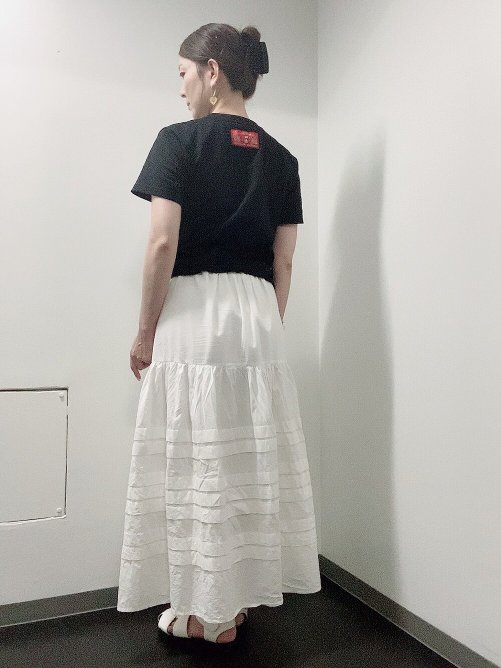 ブラック系のTシャツ/カットソー、ホワイト系のスカート、ホワイト系のサンダルを着用したレディースの夏コーディネートの3枚目の写真