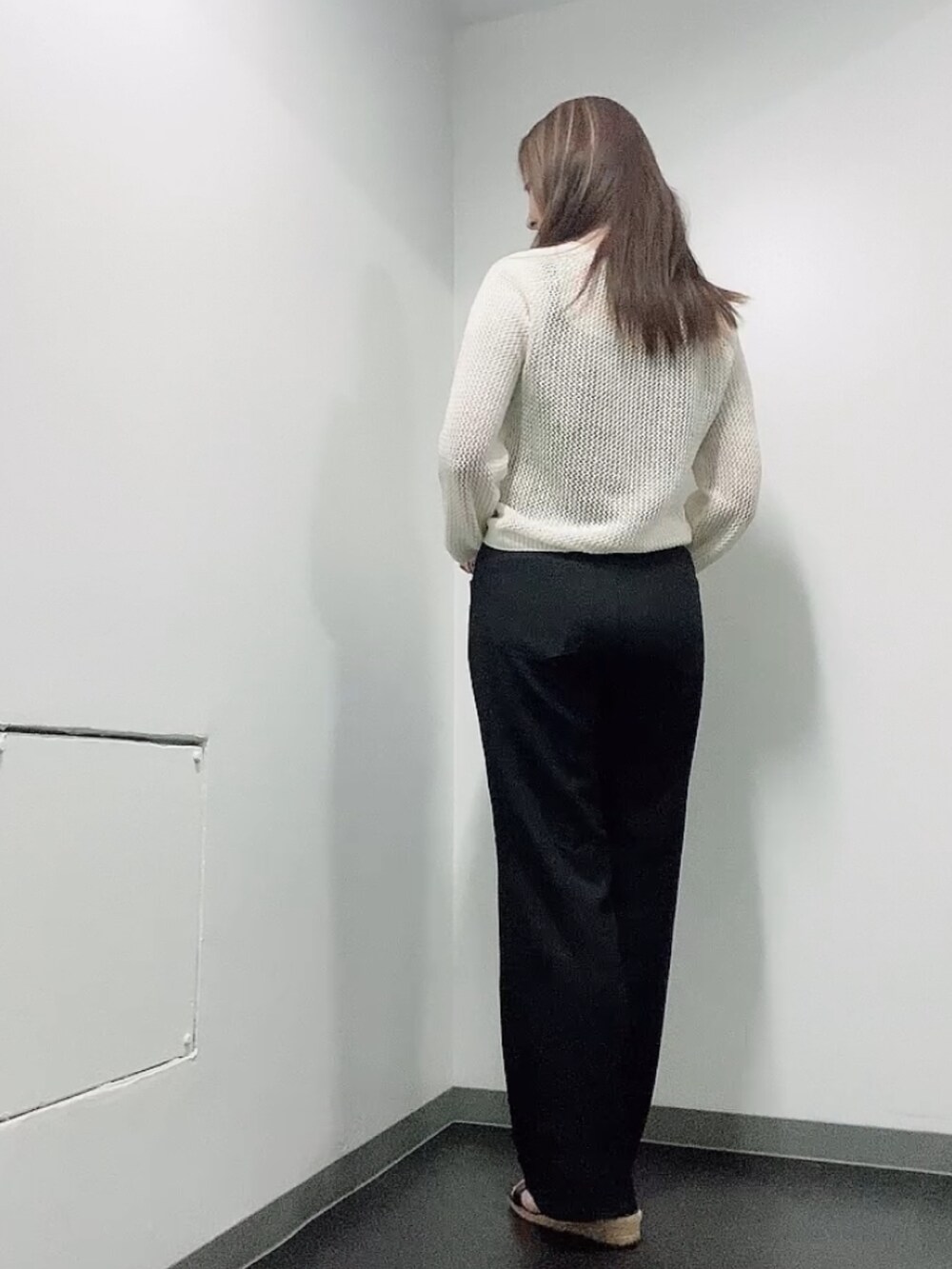 ホワイト系のニット/セーター、ブラック系のタンクトップ、ブラック系のスラックスを着用したレディースの夏コーディネートの3枚目の写真