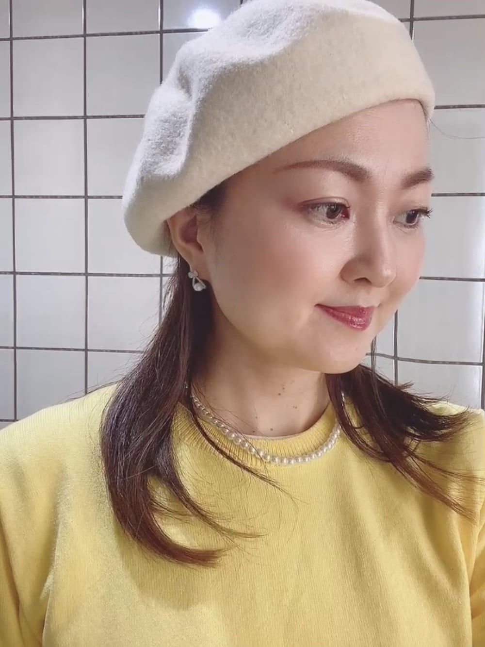 イエロー系のニット/セーター、ブラック系のスカート、ホワイト系のTシャツ/カットソーを着用したレディースの春コーディネートの3枚目の写真