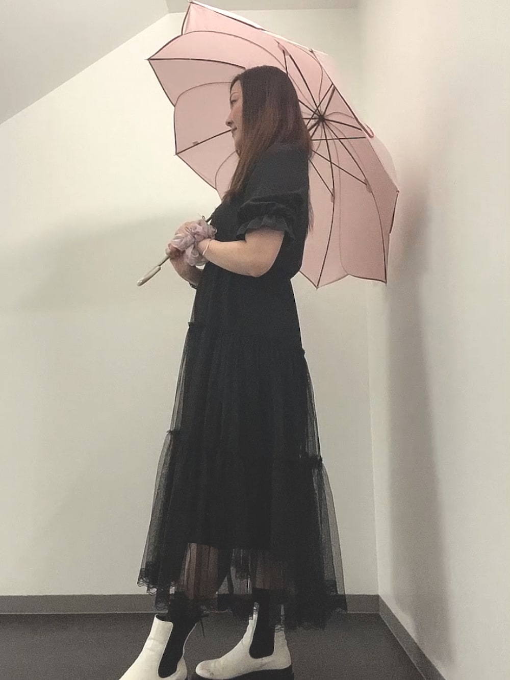 ブラック系のワンピース、ホワイト系のレインシューズ、ホワイト系のピアス（両耳用）を着用したレディースの秋コーディネートの2枚目の写真