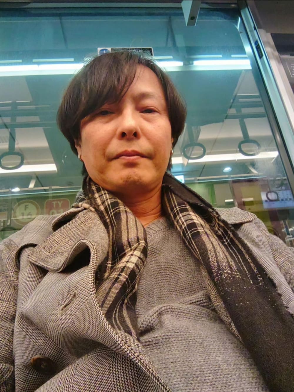 グレー系のスラックス、グレー系のニット/セーター、グレー系のトレンチコートを着用したメンズの冬コーディネートの3枚目の写真