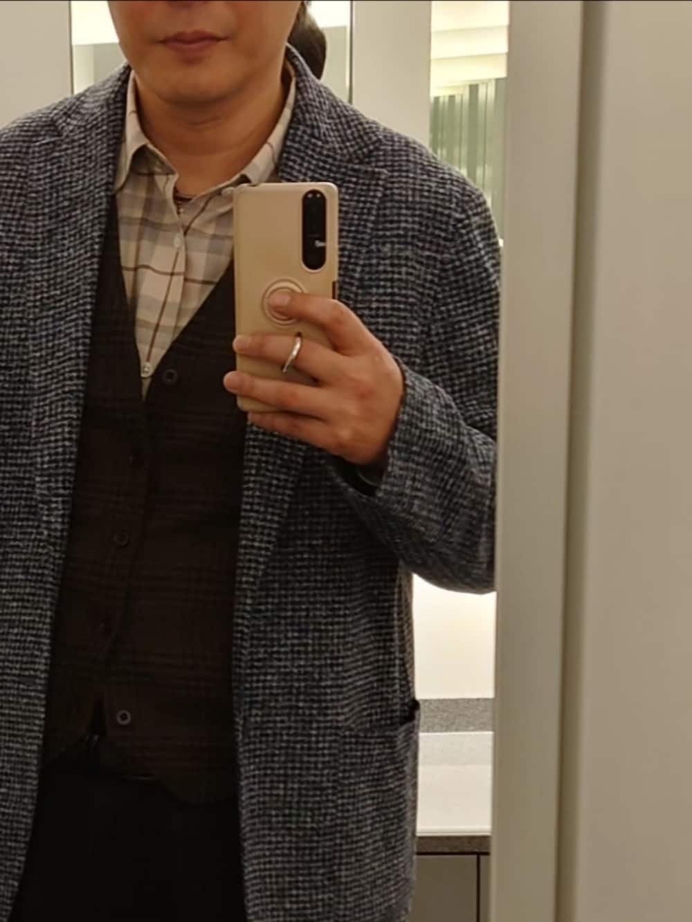 ブラック系のステンカラーコート、ブラウン系のブーツ、ブルー系のテーラードジャケットを着用したメンズの冬コーディネートの4枚目の写真