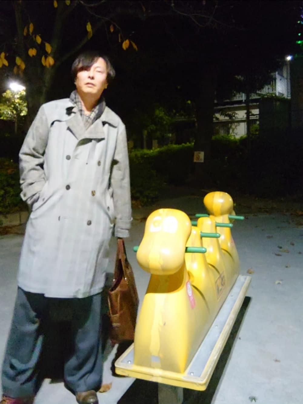 グレー系のスラックス、グレー系のニット/セーター、グレー系のトレンチコートを着用したメンズの冬コーディネートの2枚目の写真