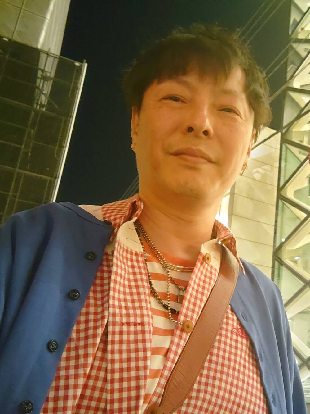 レッド系のシャツ/ブラウス、ブルー系のデニムパンツ、ブラック系のスニーカーを着用したメンズの夏コーディネートの2枚目の写真