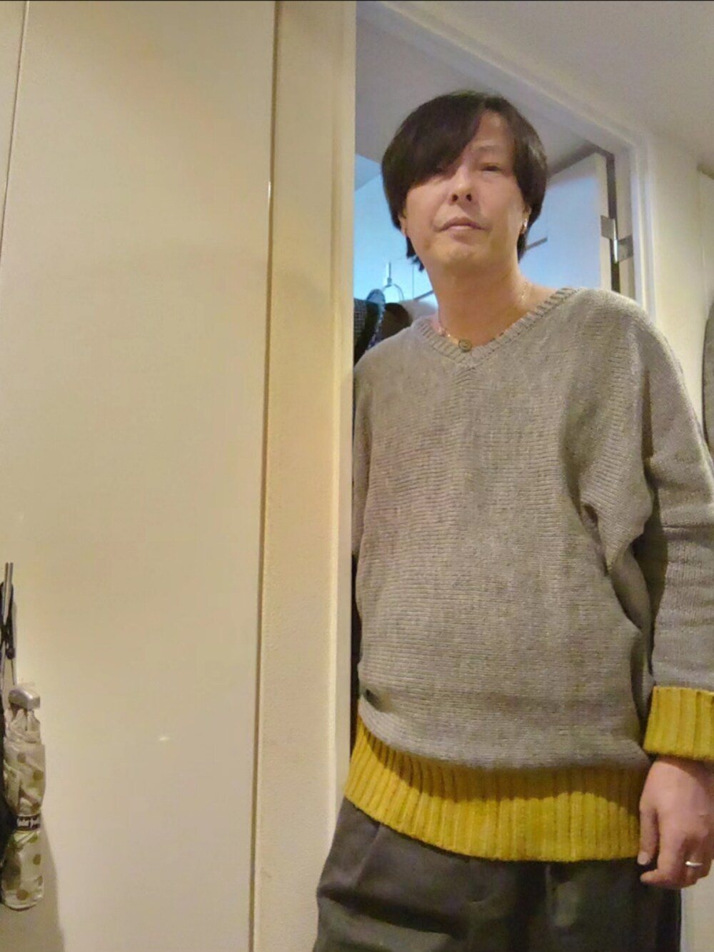 グレー系のスラックス、グレー系のニット/セーター、グレー系のトレンチコートを着用したメンズの冬コーディネートの5枚目の写真