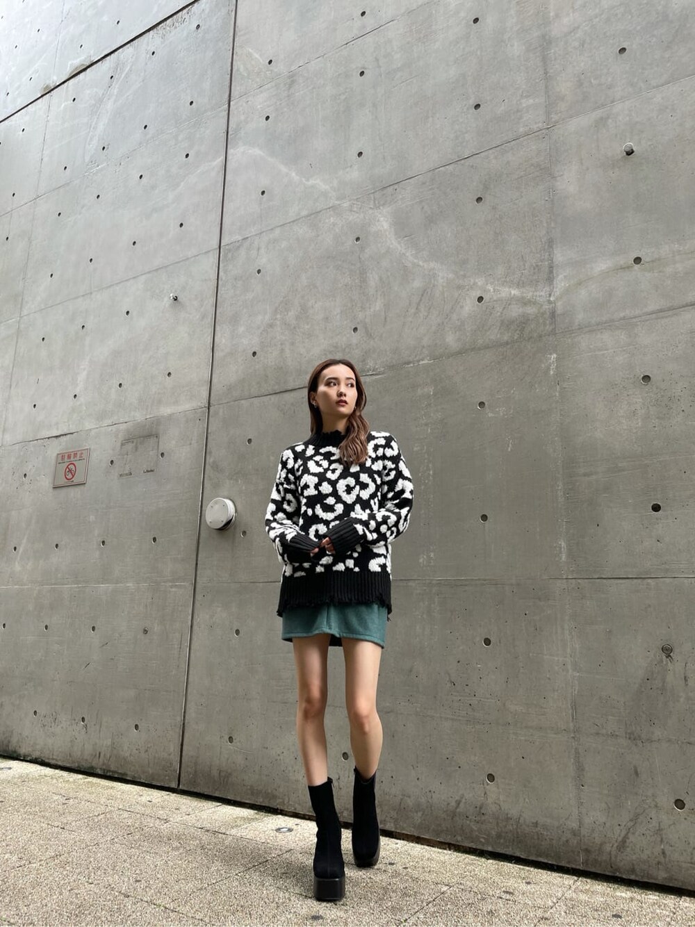 ブラック系のニット/セーター、ブラック系のブーツ、グリーン系のスカートを着用したレディースの冬コーディネートの2枚目の写真