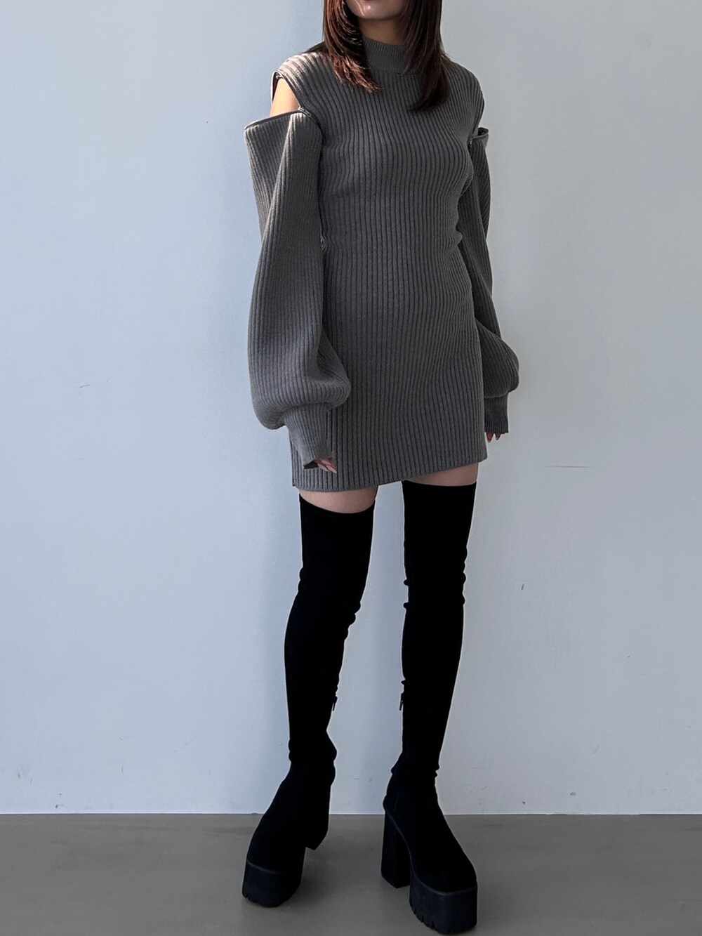 グレー系のワンピース、ブラック系のブーツを着用したレディースの冬コーディネートの2枚目の写真