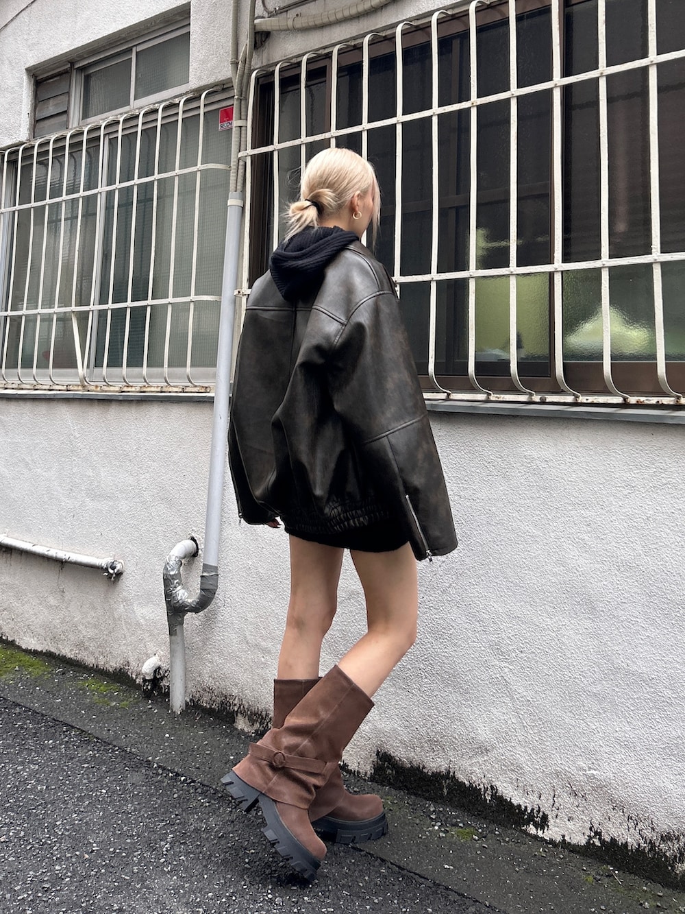 ブラック系のブルゾン、ブラウン系のブーツ、ブラック系のニット/セーターを着用したレディースの秋コーディネートの2枚目の写真