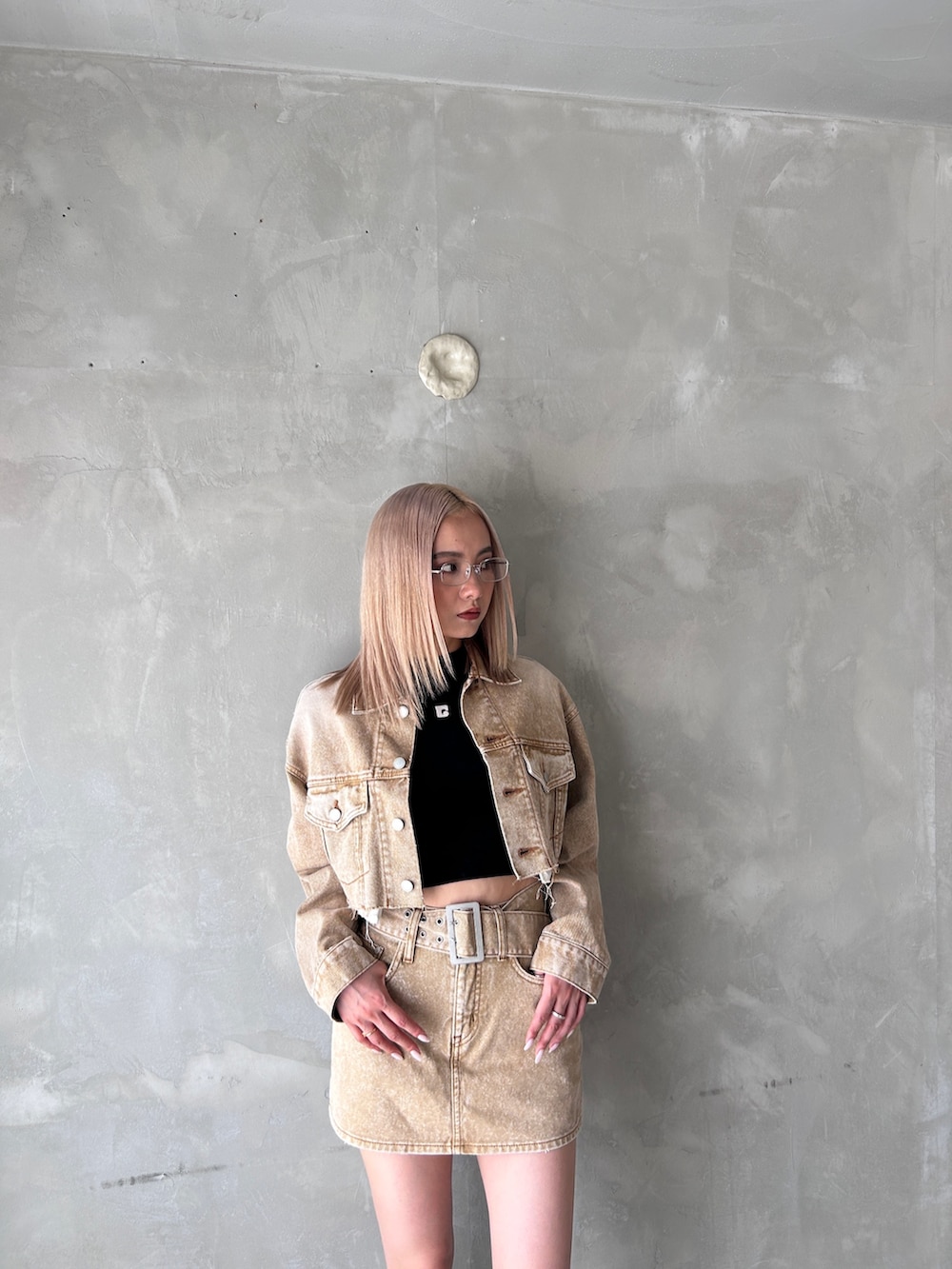 ベージュ系のデニムスカート、ベージュ系のデニムジャケット、ブラック系のブーツを着用したレディースの夏コーディネートの2枚目の写真