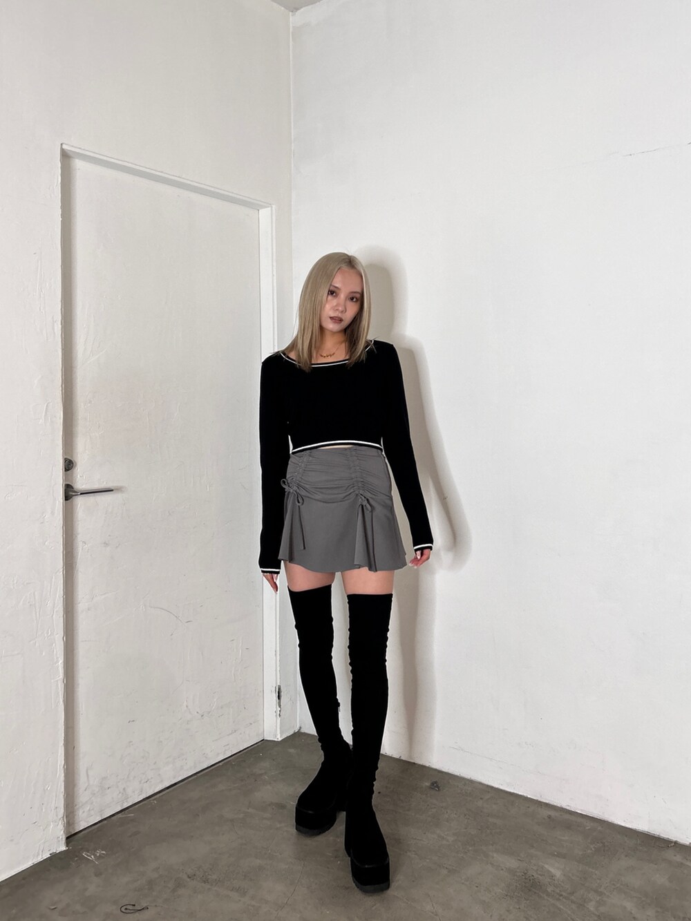 ブラック系のニット/セーター、グレー系のスカート、ブラック系のブーツを着用したレディースの秋コーディネートの2枚目の写真