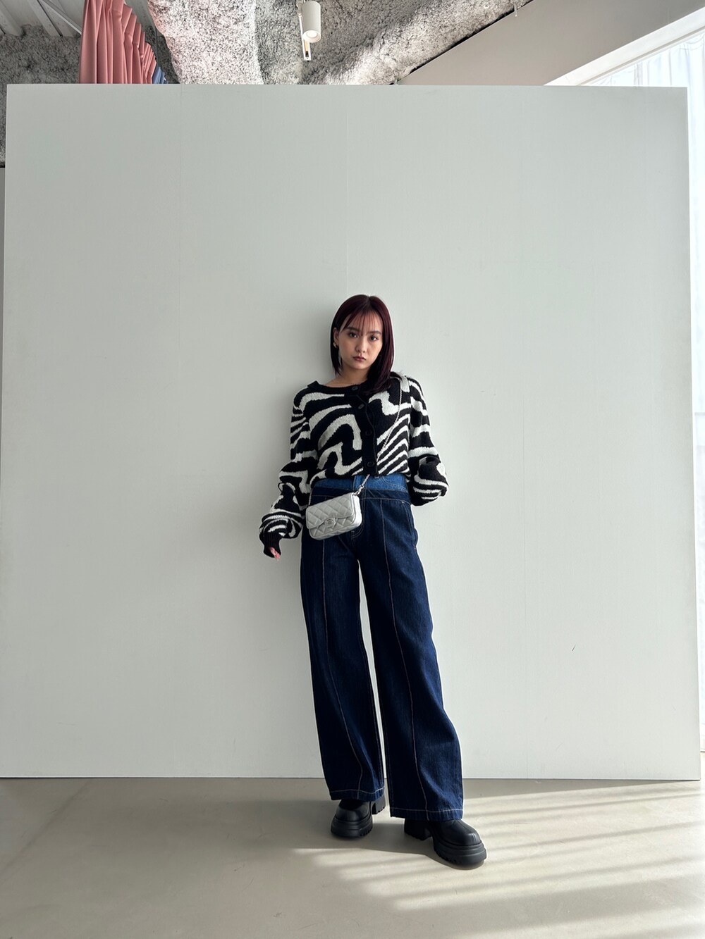 ブラック系のカーディガン/ボレロ、ブルー系のデニムパンツ、ブラック系のブーツを着用したレディースの冬コーディネートの2枚目の写真