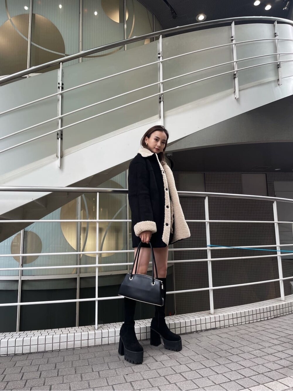 ブラック系のムートンコート、ブラック系のブーツを着用したレディースの秋コーディネートの2枚目の写真