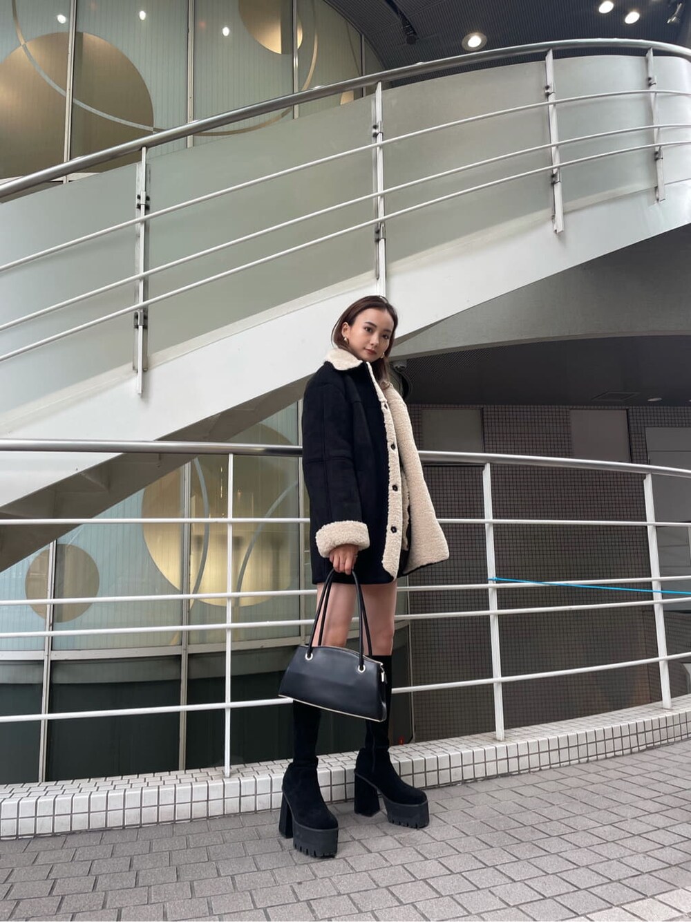 グリーン系のニット/セーター、ブラック系のスカート、ブラック系のムートンコートを着用したレディースの冬コーディネートの3枚目の写真