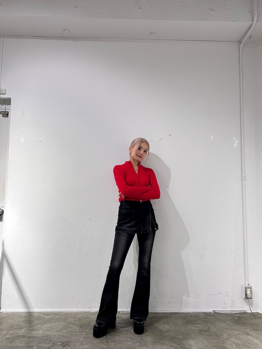 レッド系のニット/セーター、ブラック系のデニムパンツ、ブラック系のブーツを着用したレディースの秋コーディネートの2枚目の写真