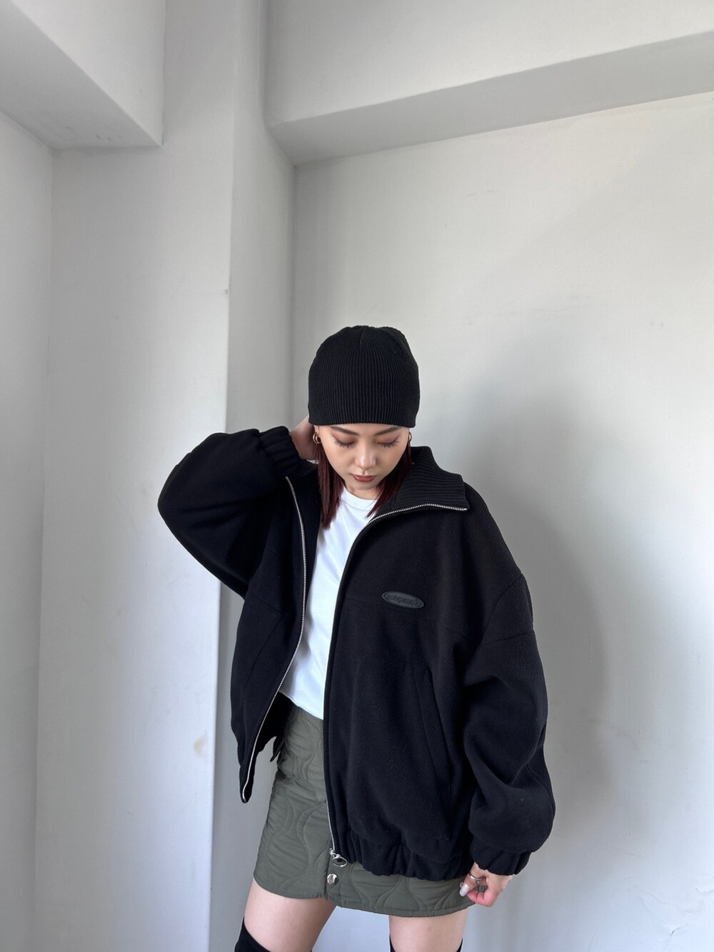 ブラック系のブルゾン、グリーン系のスカート、ホワイト系のTシャツ/カットソーを着用したレディースの秋コーディネートの2枚目の写真