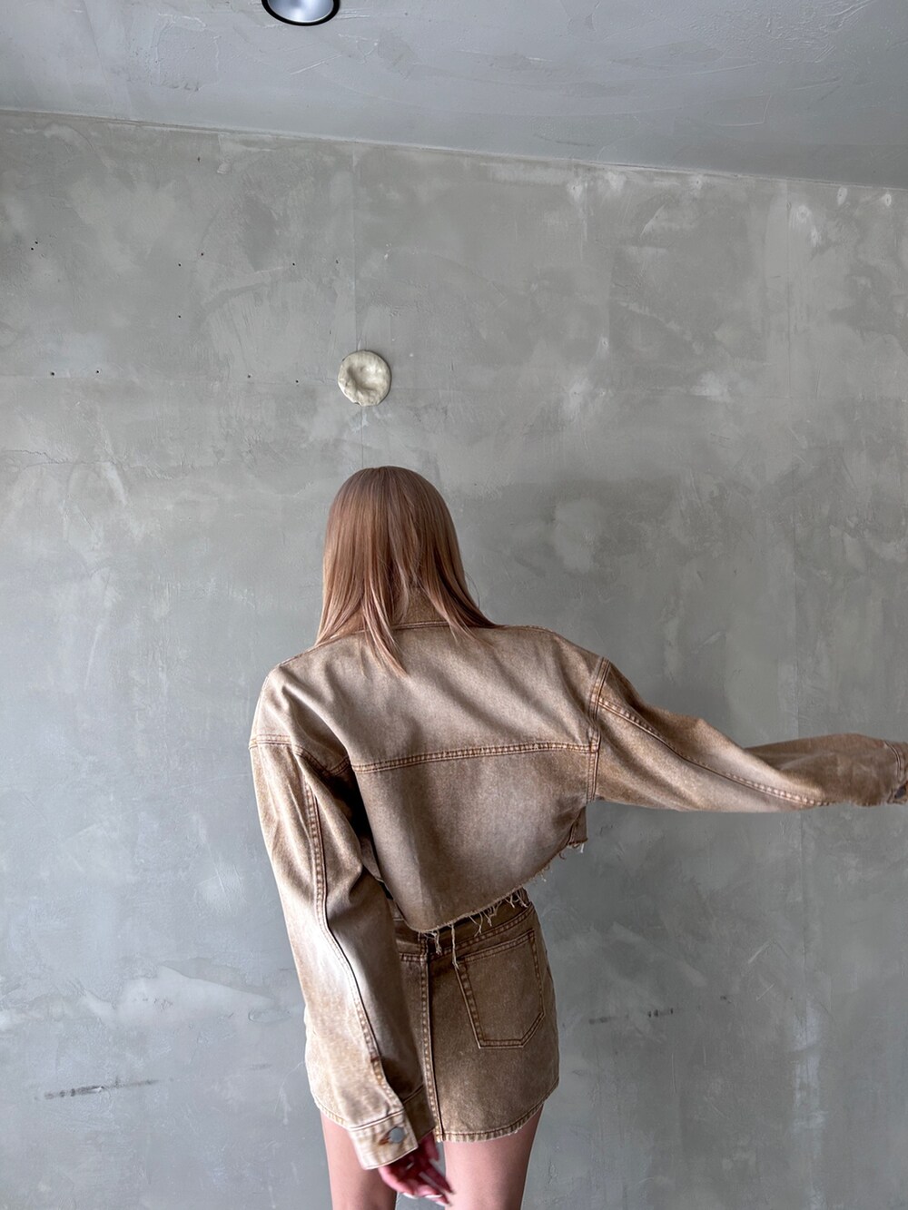 ベージュ系のデニムスカート、ベージュ系のデニムジャケット、ブラック系のブーツを着用したレディースの夏コーディネートの4枚目の写真