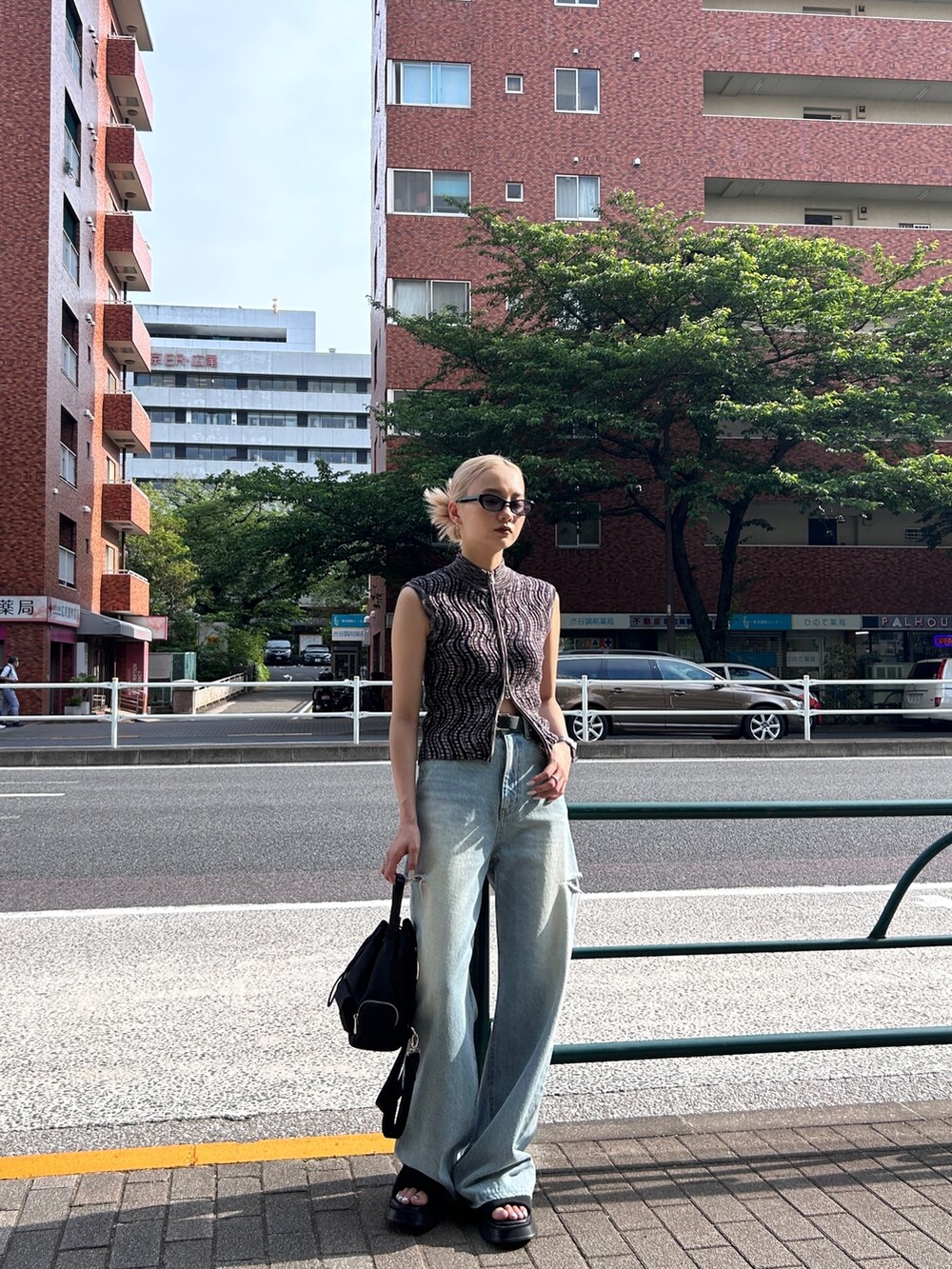 ブラウン系のタンクトップ、ブルー系のデニムパンツ、ブラック系のバッグを着用したレディースの春コーディネートの3枚目の写真