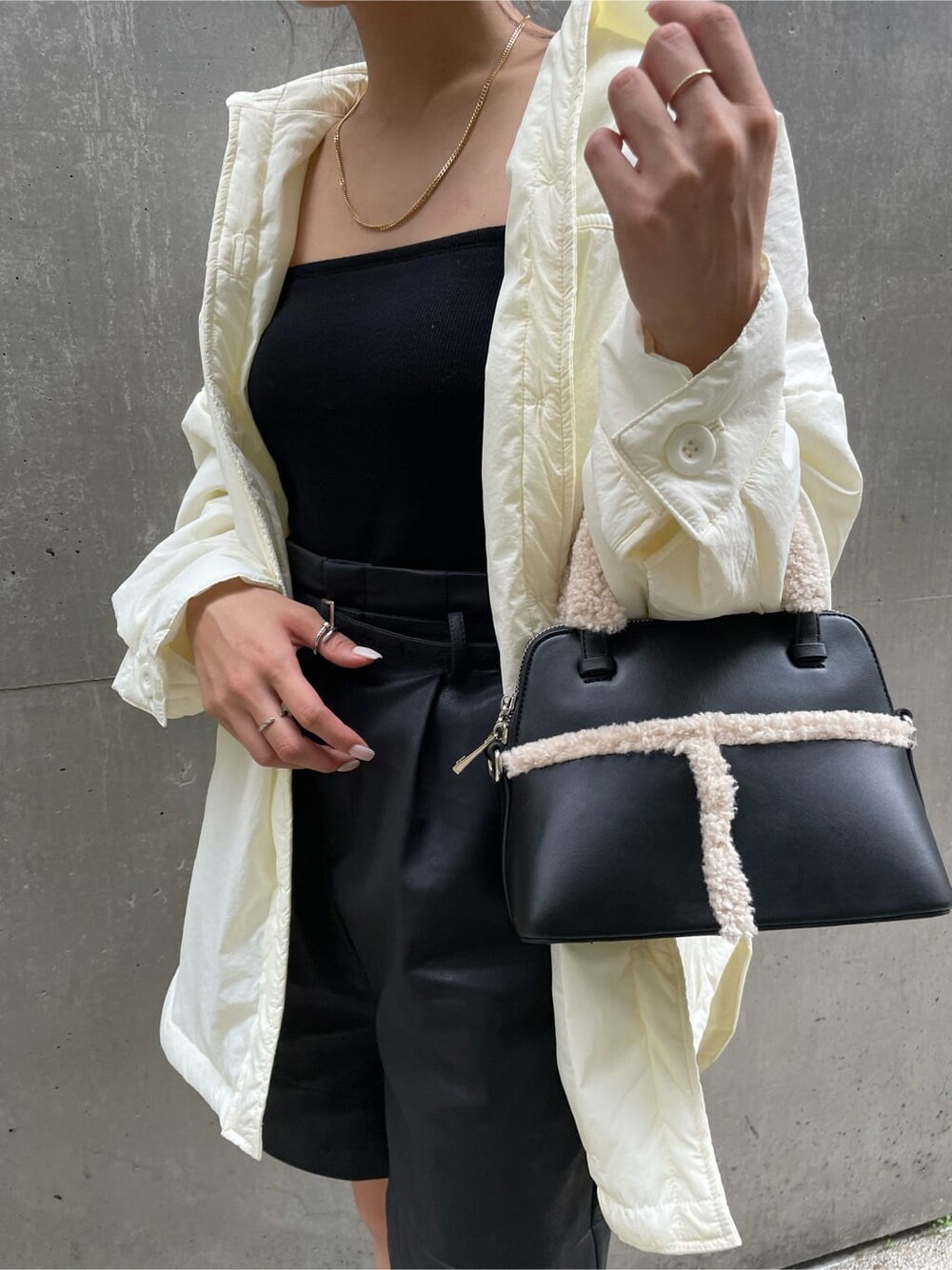 ホワイト系のハンドバッグ、ブラック系のハンドバッグ、グリーン系のニット/セーターを着用したレディースの秋コーディネートの4枚目の写真