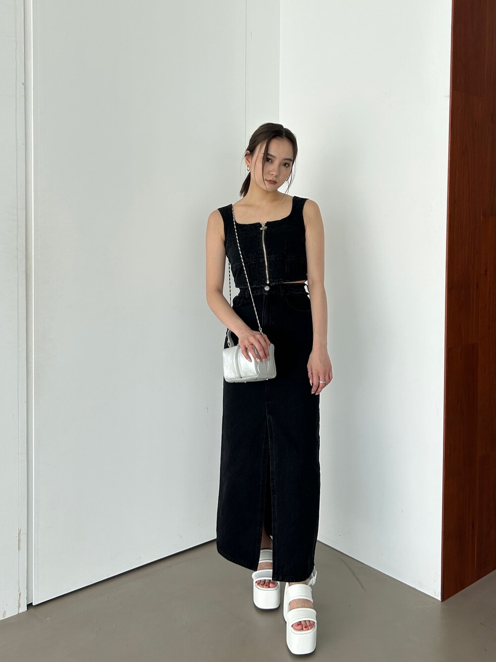 ブラック系のキャミソール、ブラック系のデニムスカート、ホワイト系のサンダルを着用したレディースの春コーディネートの3枚目の写真
