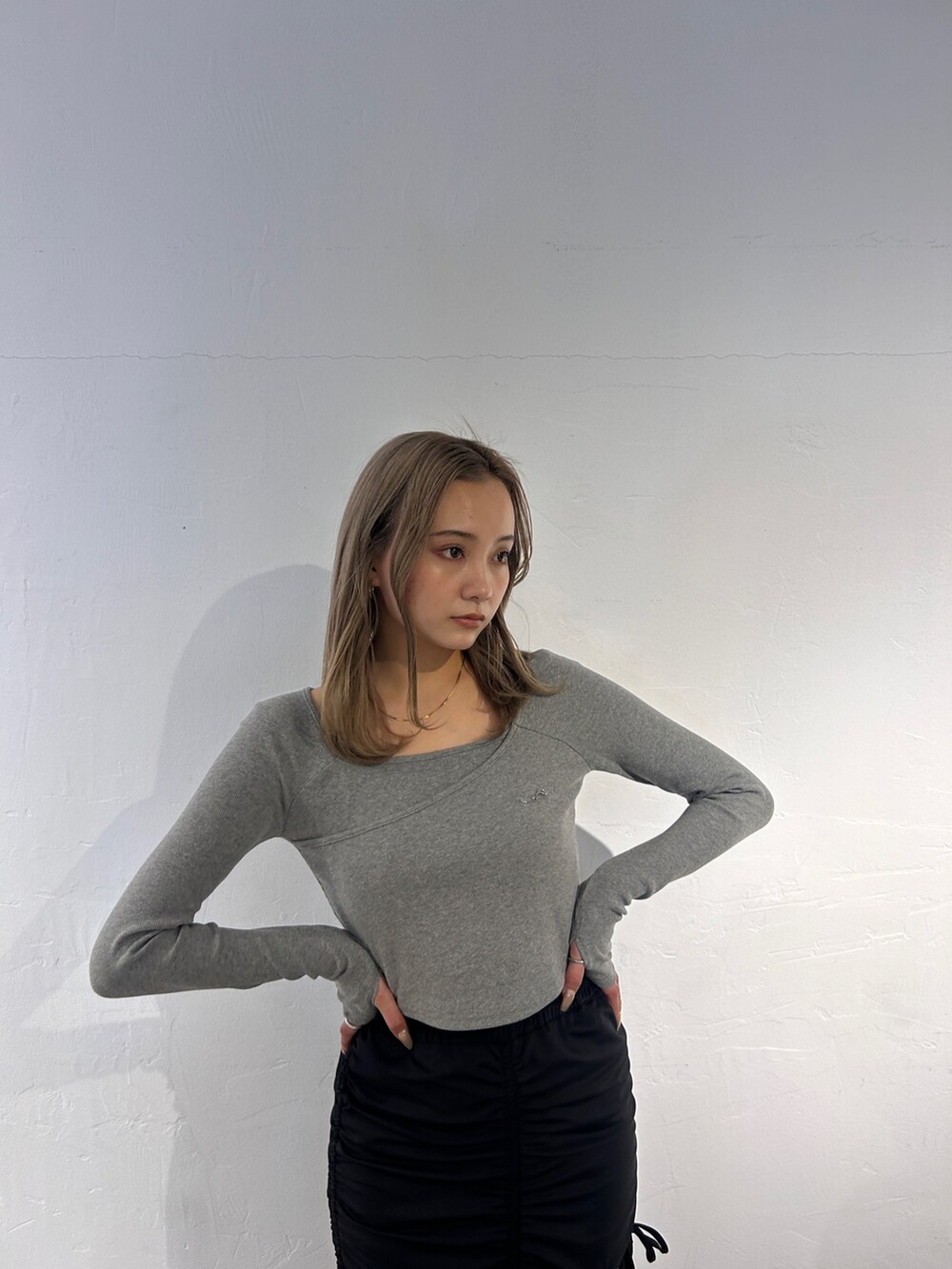 グレー系のTシャツ/カットソー、ブラック系のスカート、ブラック系のブーツを着用したレディースの冬コーディネートの3枚目の写真